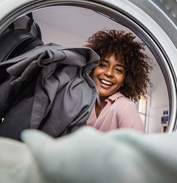 a woman looking at her clothes in the washing machine